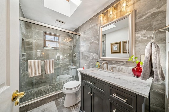 full bath with vanity, tile walls, toilet, and a stall shower