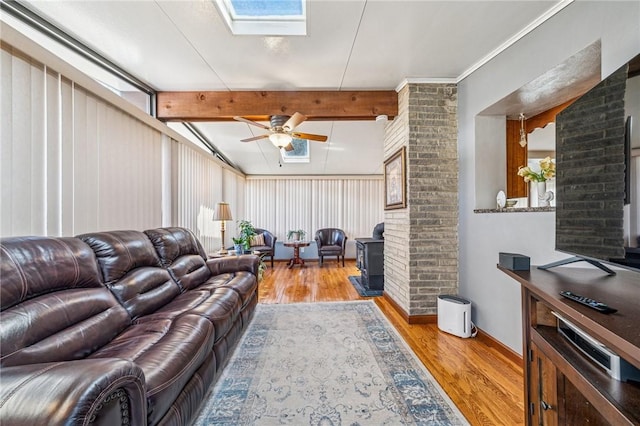 living room with beam ceiling, a skylight, wood finished floors, and ceiling fan