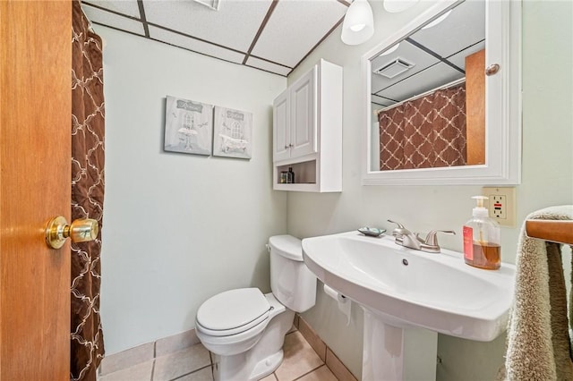 bathroom featuring visible vents, toilet, tile patterned floors, a paneled ceiling, and a sink