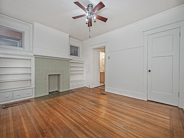 unfurnished living room with visible vents, wood finished floors, a fireplace, and ornamental molding