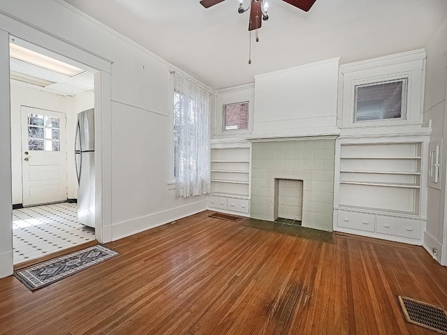 unfurnished living room featuring visible vents, a tile fireplace, baseboards, and wood finished floors