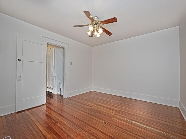 empty room featuring a ceiling fan, baseboards, and wood finished floors