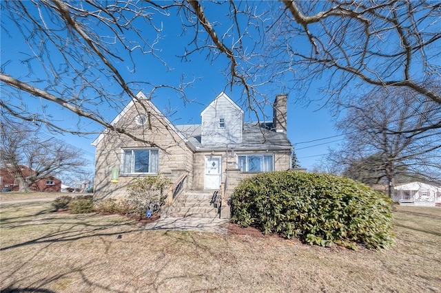 view of front of property featuring stone siding, a chimney, and a front lawn