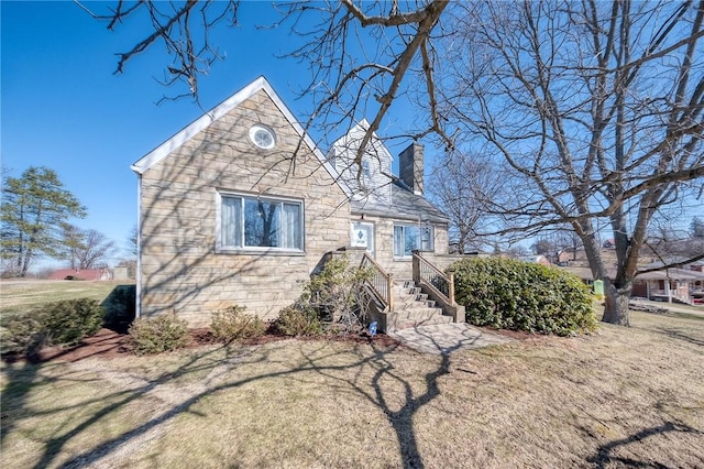 view of front of home featuring a front lawn, stone siding, and a chimney