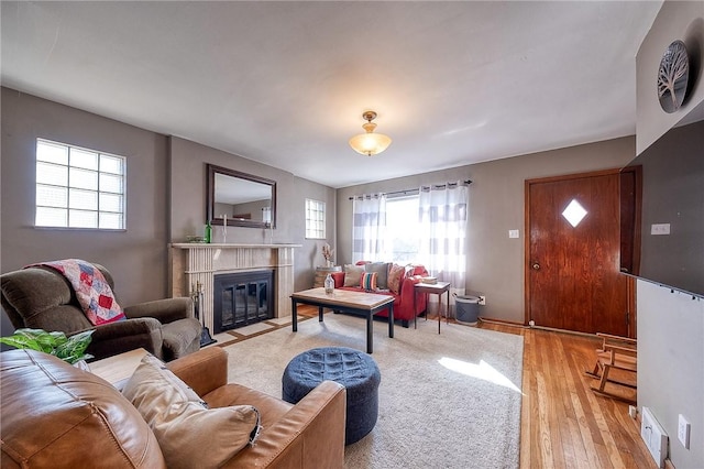 living room featuring wood finished floors, a fireplace with flush hearth, a healthy amount of sunlight, and visible vents