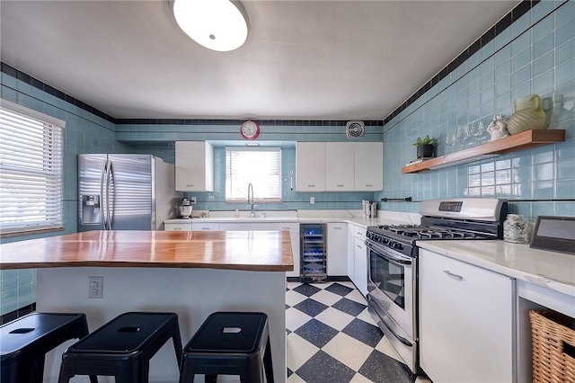 kitchen with wood counters, white cabinetry, stainless steel appliances, wine cooler, and light floors