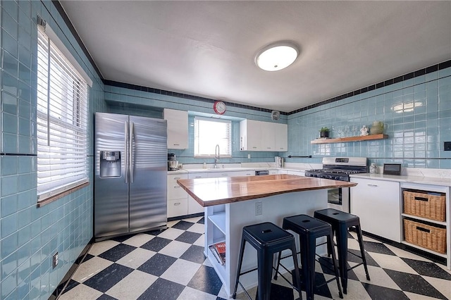 kitchen with open shelves, stainless steel appliances, and dark floors