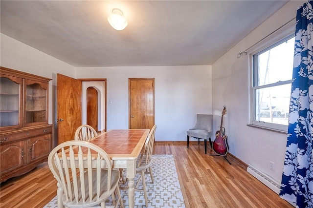 dining room featuring light wood finished floors, baseboards, and baseboard heating