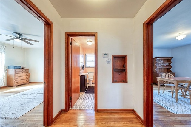 hall featuring light wood-type flooring and baseboards