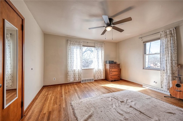 interior space with multiple windows, wood finished floors, visible vents, and a baseboard radiator