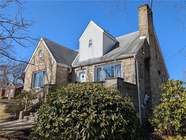 view of front facade with stone siding and a chimney