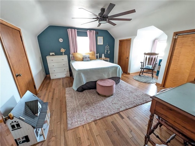 bedroom featuring lofted ceiling, light wood-style flooring, a ceiling fan, and baseboards