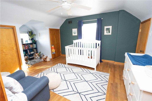 bedroom with ceiling fan, visible vents, lofted ceiling, and wood finished floors