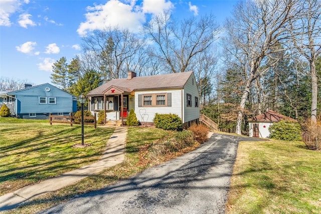 bungalow-style home with a chimney and a front lawn