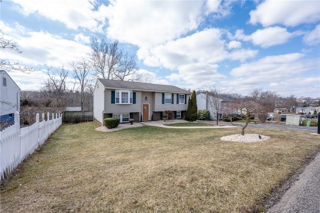 raised ranch featuring brick siding, a front yard, and fence