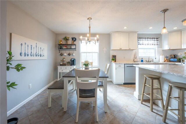 dining space featuring a wealth of natural light, baseboards, a textured ceiling, and a chandelier