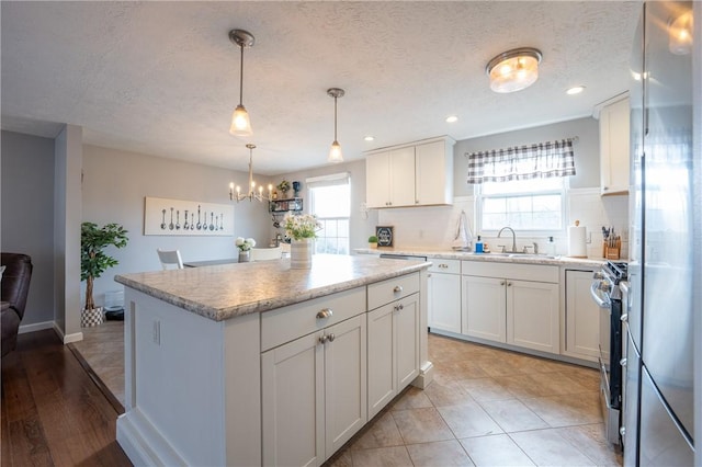 kitchen with backsplash, white cabinets, light countertops, and a sink