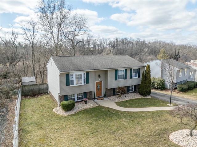 split foyer home with brick siding, driveway, a front lawn, and fence