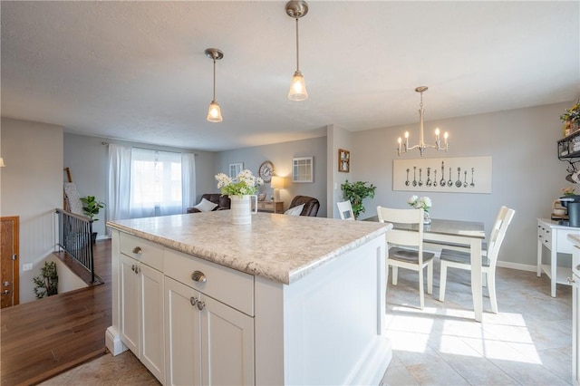 kitchen featuring decorative light fixtures, a kitchen island, light countertops, and white cabinetry