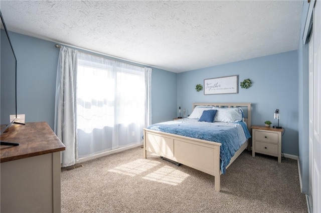 bedroom featuring baseboards, carpet, visible vents, and a textured ceiling