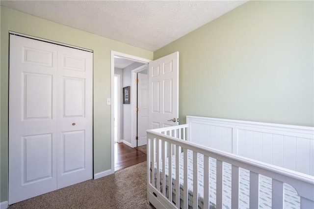 bedroom featuring a closet, dark carpet, and a textured ceiling