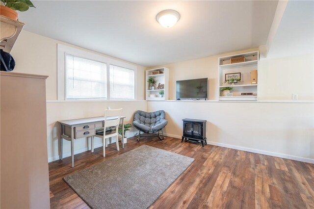 sitting room featuring baseboards, wood finished floors, and a wood stove