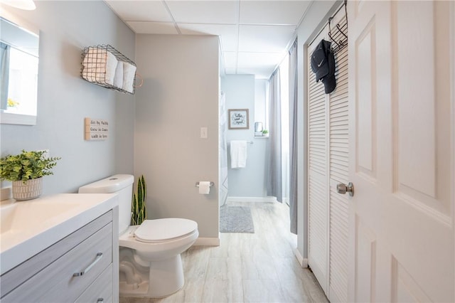 bathroom with vanity, toilet, a paneled ceiling, and baseboards