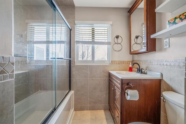 full bath with vanity, tile walls, toilet, combined bath / shower with glass door, and tile patterned floors