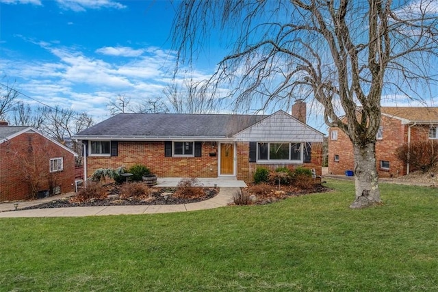 single story home featuring brick siding, a chimney, and a front yard