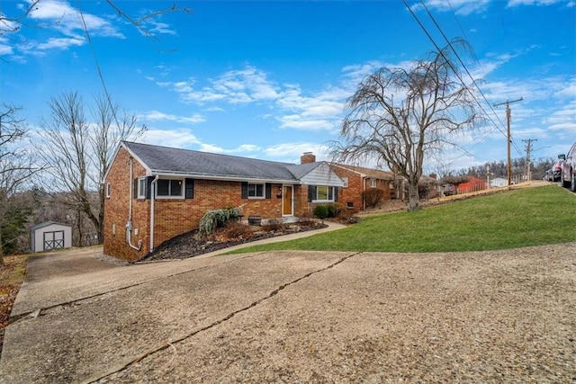 single story home featuring a front yard, an outbuilding, a chimney, concrete driveway, and brick siding