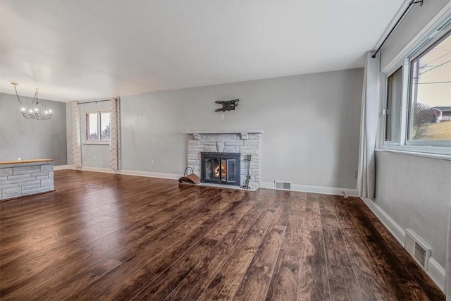 unfurnished living room with visible vents, a stone fireplace, and wood finished floors