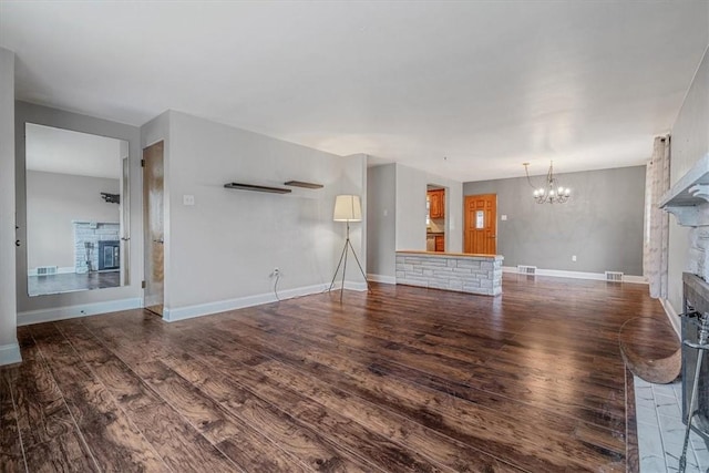 unfurnished living room with a chandelier, visible vents, a fireplace, and wood finished floors