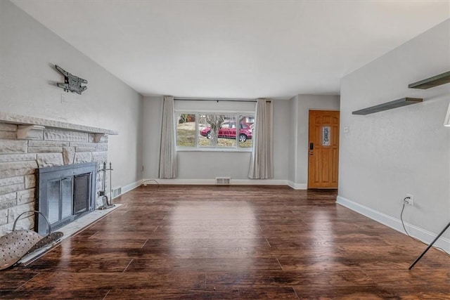 unfurnished living room with visible vents, baseboards, a stone fireplace, and wood finished floors