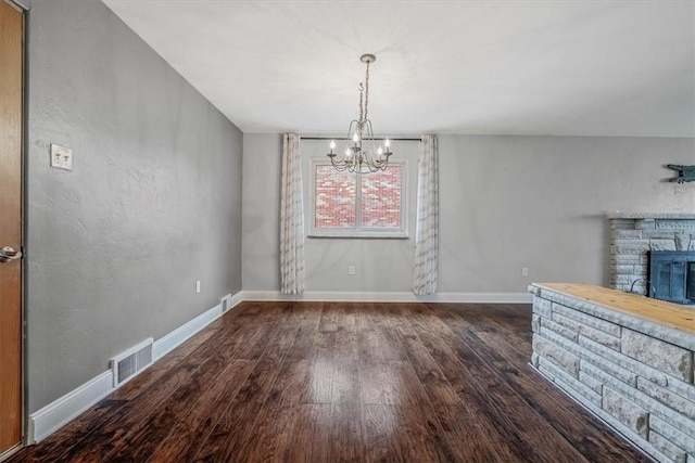 unfurnished dining area featuring wood finished floors, a fireplace, visible vents, and baseboards