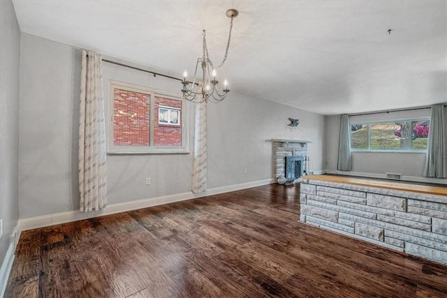 unfurnished living room with visible vents, a fireplace, baseboards, and wood finished floors