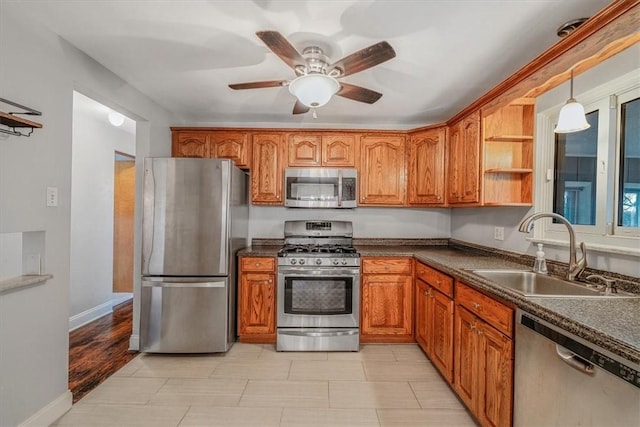 kitchen featuring dark countertops, ceiling fan, brown cabinets, stainless steel appliances, and a sink