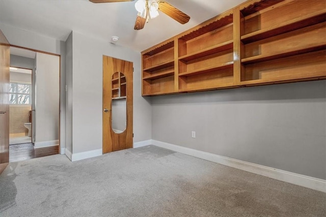 unfurnished bedroom with ensuite bath, carpet flooring, baseboards, and ceiling fan