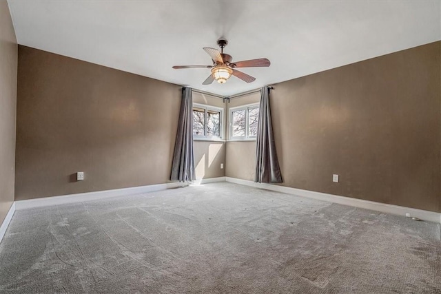 carpeted spare room featuring a ceiling fan and baseboards