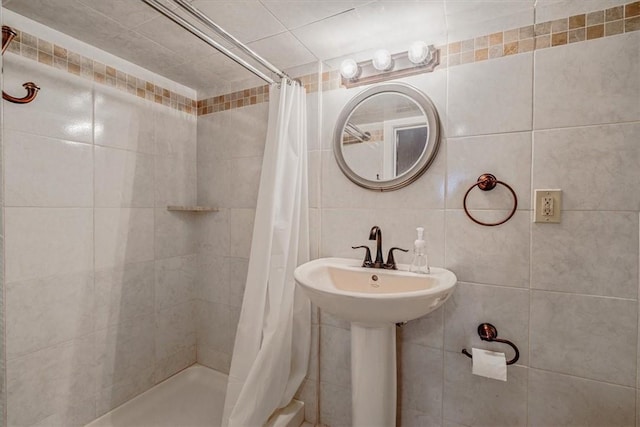 bathroom featuring a sink, tile walls, and a stall shower