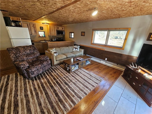 living room with a wainscoted wall, baseboard heating, and wood walls