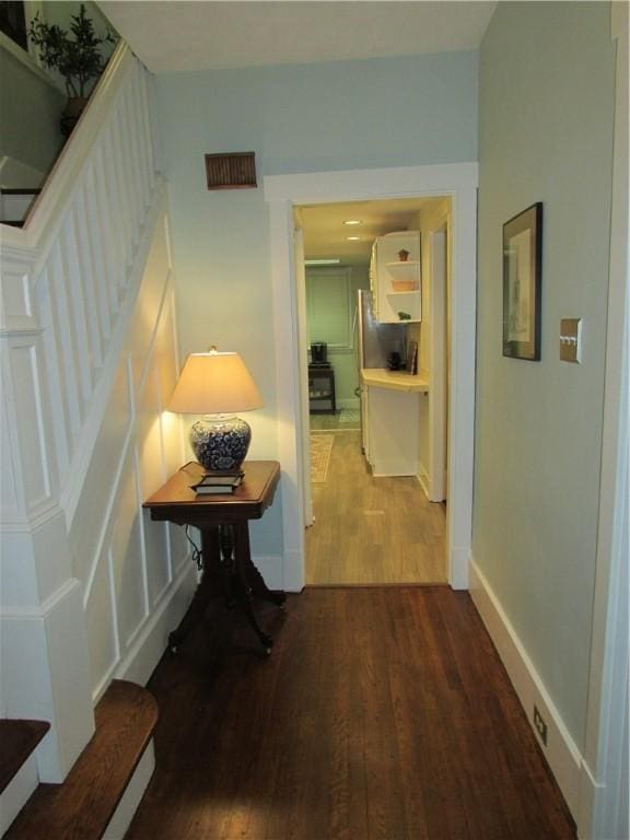 hallway featuring stairway, baseboards, visible vents, and wood finished floors