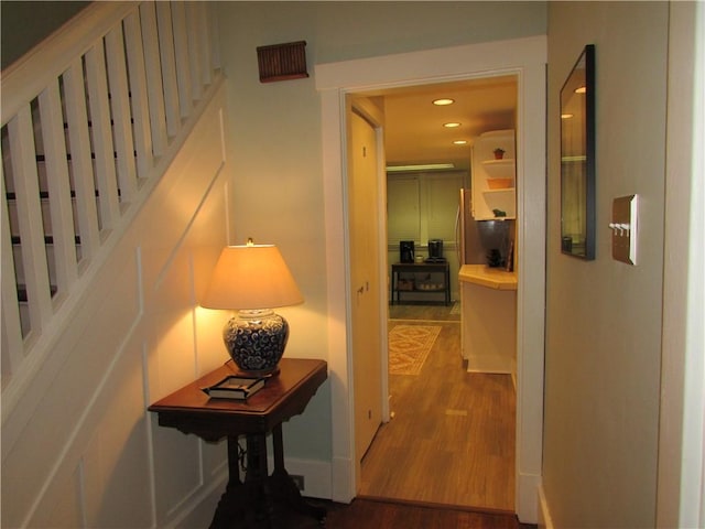 hall with recessed lighting, stairway, and wood finished floors