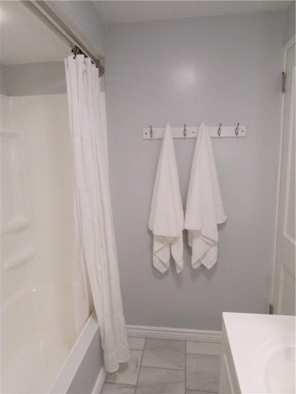 bathroom with vanity, shower / bath combination with curtain, and baseboards