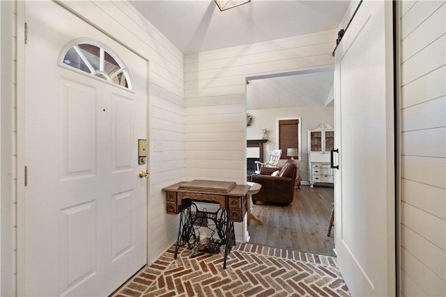 entrance foyer featuring wooden walls and brick floor