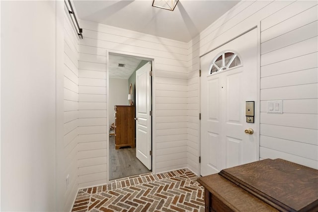 mudroom with brick floor and wooden walls