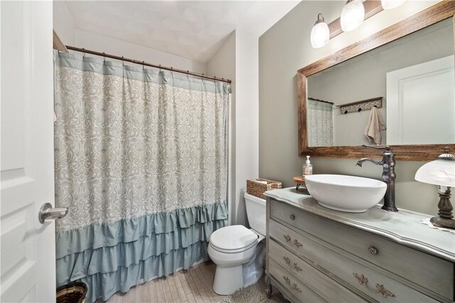 bathroom with a shower with shower curtain, toilet, wood finished floors, and vanity