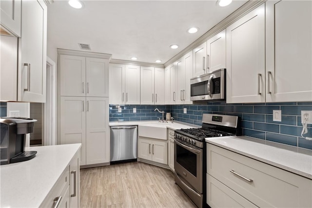 kitchen featuring tasteful backsplash, visible vents, light countertops, appliances with stainless steel finishes, and a sink