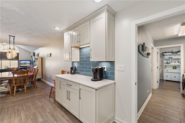 kitchen featuring backsplash, baseboards, light countertops, light wood-style flooring, and white cabinets