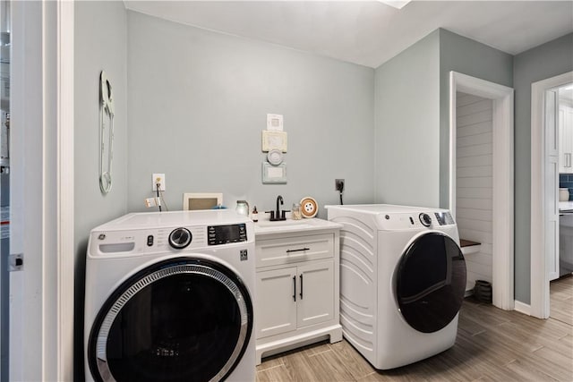 laundry room with cabinet space, wood finish floors, separate washer and dryer, and a sink