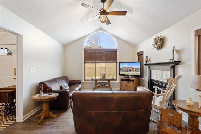 living area featuring vaulted ceiling, baseboards, a ceiling fan, and wood finished floors